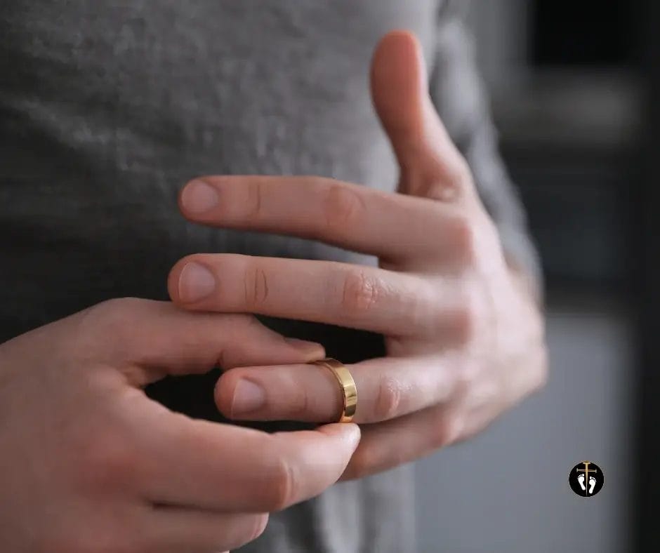 Close-up of hands removing a wedding ring, representing infidelity and the struggle with adultery